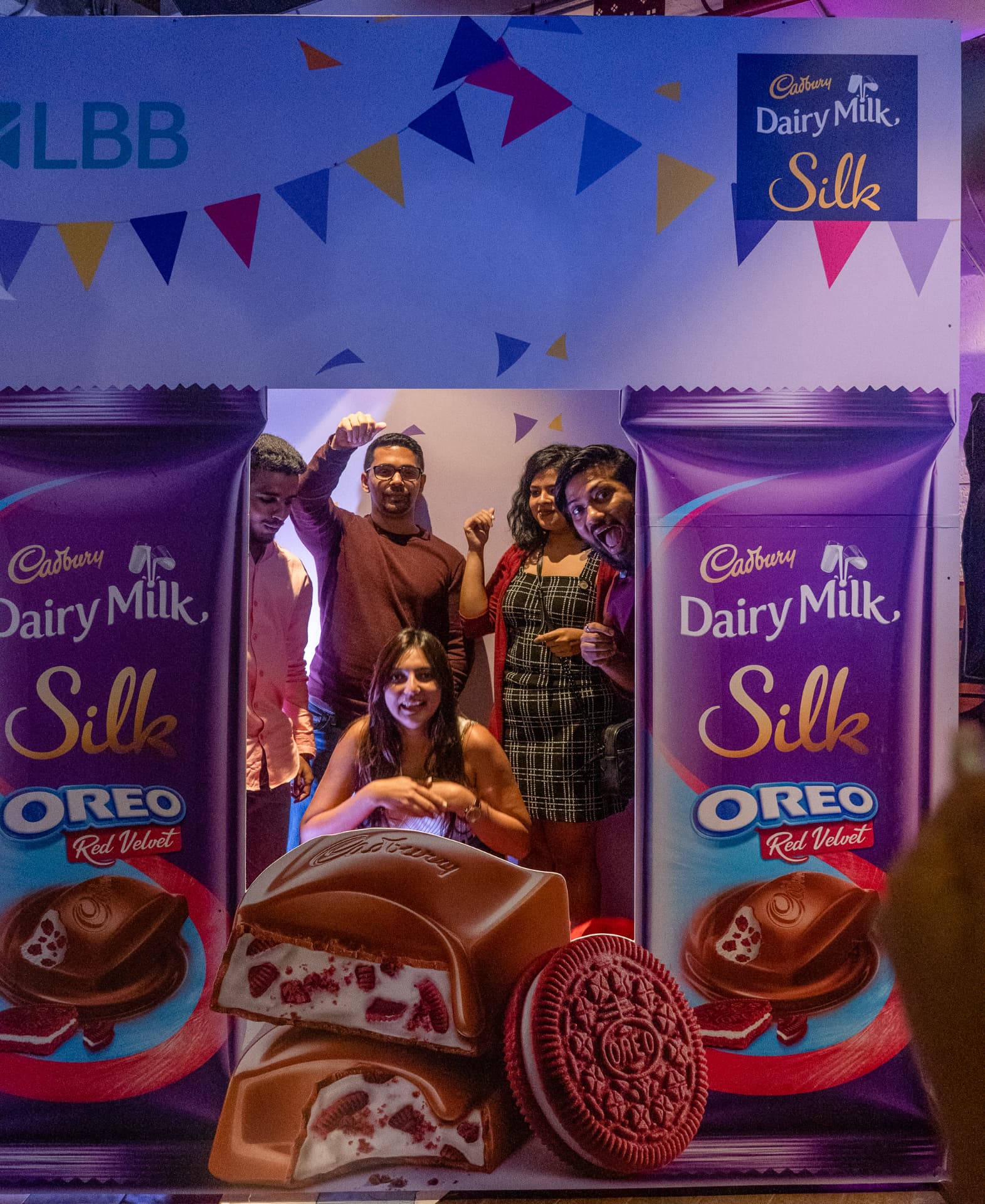 Five people posing behind a large Cadbury Silk Oreo Red Velvet chocolate bar cutout.